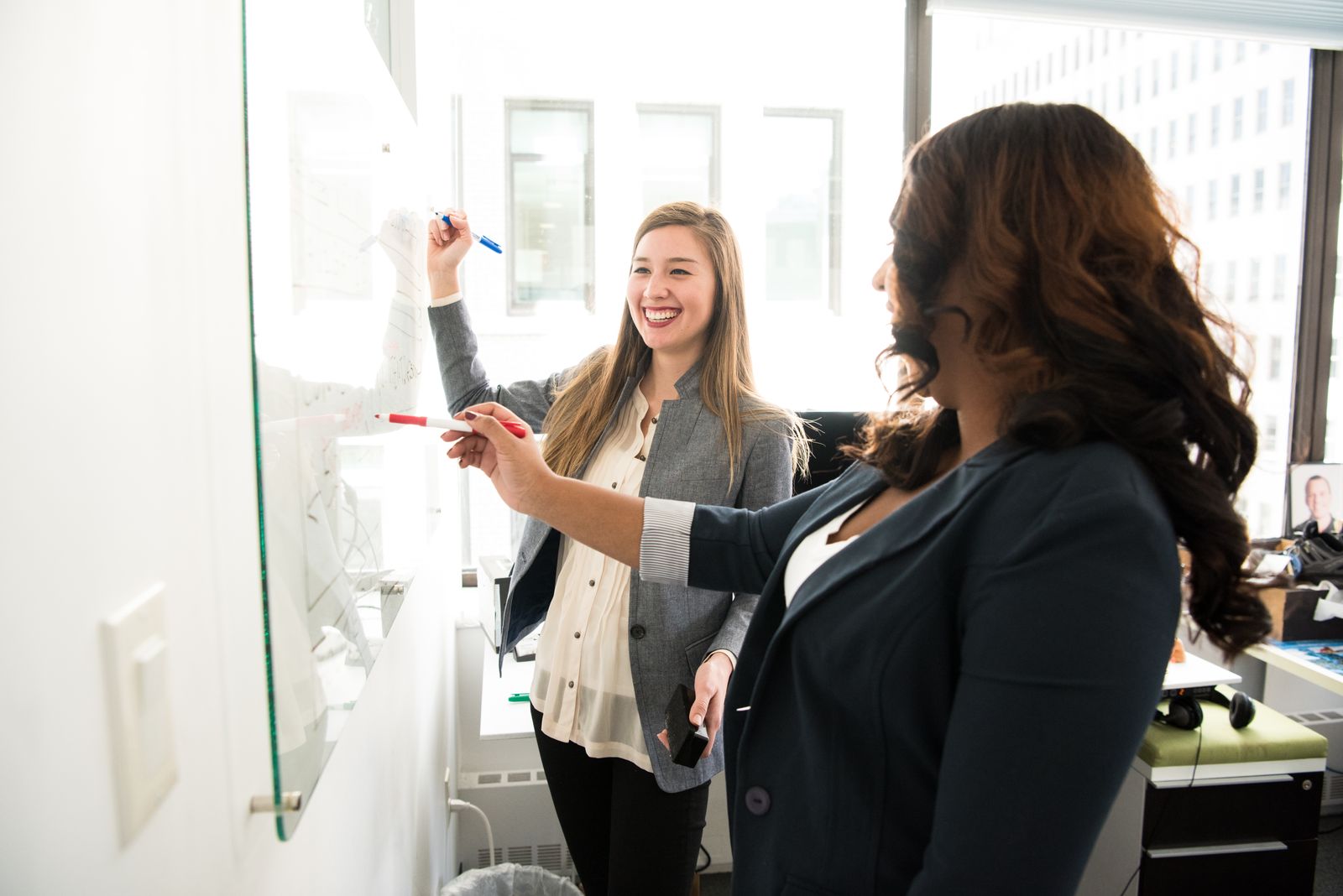 Colleagues collaborating on a design plan at a glass whiteboard